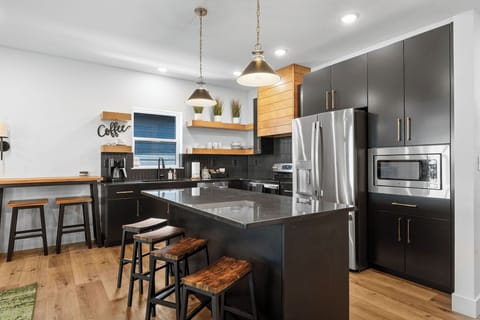 - Brew your perfect morning cup at the dedicated coffee station
- Bold black cabinetry paired with warm wood shelves for a modern touch
- Fully equipped kitchen with all essentials for your stay