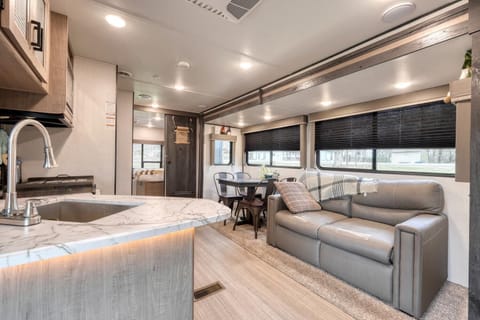 Spacious living area with plush seating, dining nook, and sleek marble counters.