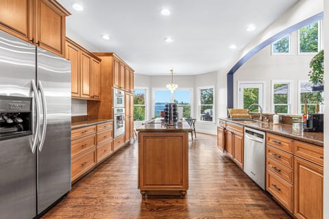 This spacious and elegant kitchen is a culinary dream, featuring warm wood cabinetry, sleek stainless steel appliances, and a central island perfect for meal prep and entertaining. Whether you're cooking, dining, or enjoying a glass of wine, this kitchen is designed for both comfort and sophistication.