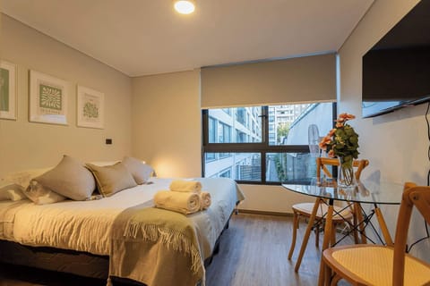 Relax in this cozy bedroom with a city view, featuring a comfy bed, chic decor, and a stylish dining area.