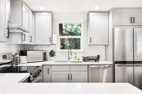 Bright and inviting, this kitchen is designed for convenience and elegance. A large window fills the space with natural light, highlighting the spacious countertops and high-end stainless steel appliances.