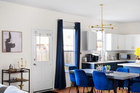 This beautifully designed open-concept dining and kitchen area features a stylish wood table, plush blue velvet chairs, and a chic gold chandelier. Perfect for enjoying home-cooked meals or takeout from Round Rock’s top eateries.