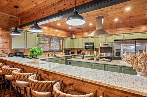 The large fully equipped kitchen has an island, a bar, 2 large refrigerators, 2 dishwashers, 2 sinks, 2 ovens, and an electric cooktop.