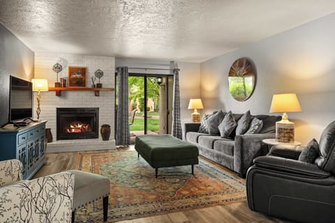 Cozy living room with fireplace, stylish seating, and backyard views through sliding doors.