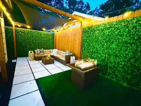 Your private oasis—warm lights, lush greenery, and a cozy fire.
