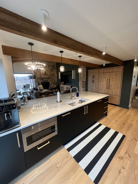 Living room view from kitchen. Stone fireplace, Sub zero refrigerator, peninsula with seating and workstation sink.