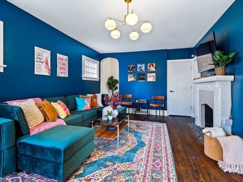 Vibrant living room w/ bold blue walls, colorful seating & a cozy space to gather and unwind