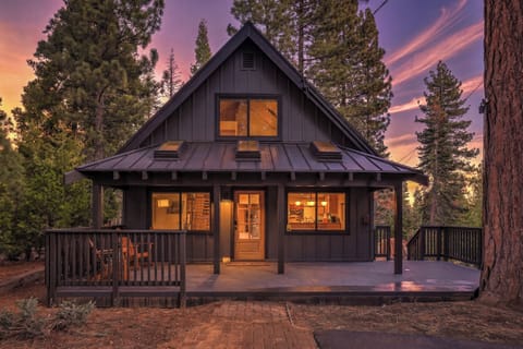 Cabin exterior at sunset with warm lights and mountain lodge charm.
