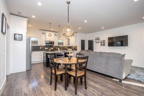 Welcome to the bright and spacious open-concept heart of the home! This view shows the dining area, cozy living room with a large couch, and the modern kitchen island.