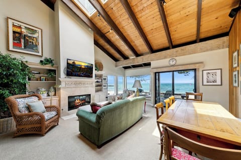 Relax in your waterfront living space where exposed beams frame stunning sea views, while the fireplace adds warmth to cozy evenings.