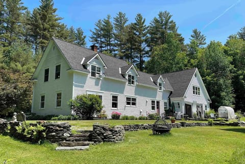 - Charming white farmhouse surrounded by greenery   - Spacious lawn with stone steps and rustic walls   - Peaceful retreat nestled by tall pine trees