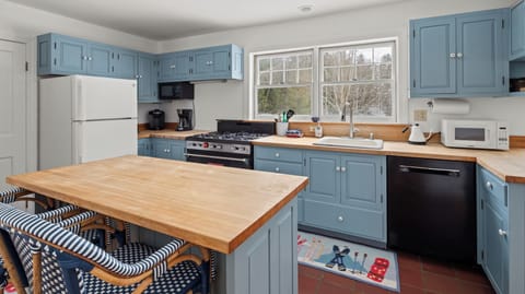 - Kitchen with blue cabinets and wood countertops   - Gas stove and modern appliances ready for use   - Bright functional layout for home cooked meals