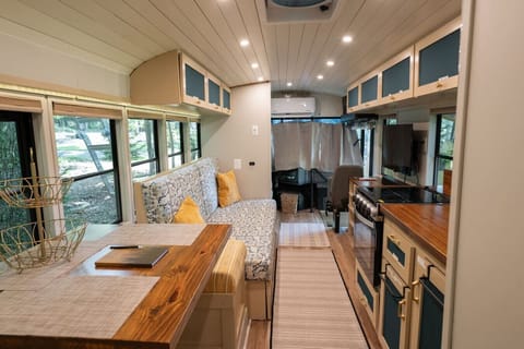 Step inside this cozy skoolie retreat, where modern comfort meets rustic charm. Stylish seating, and a dining nook, this thoughtfully designed space offers everything you need for a relaxing getaway—plus beautiful wood accents and natural light!