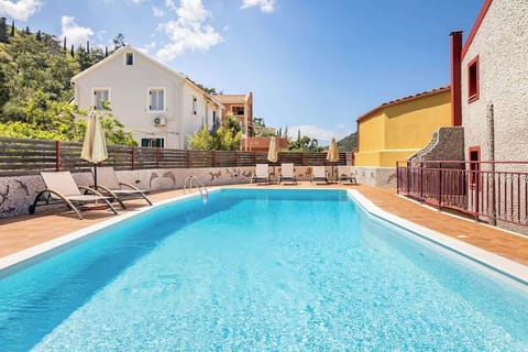 Outdoor Shared Swimming Pool with Panoramic Sea Views – A sparkling turquoise pool surrounded by lush greenery, perfect for relaxing and soaking up the Mediterranean sun.