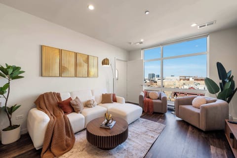 Sunlit living room w/ cozy seating, warm wood accents & an open, airy feel.