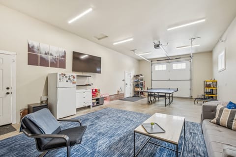 Game room with enormous TV, multiple couches, pingpong table, electronic darts, and Wii game system