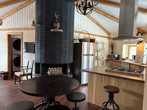 Open layout with dining table next to the couch, facing fireplace and kitchen.