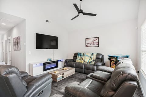 Living room with Smart TV with streaming, Xbox 1S with games and Blu-ray, electric fireplace, power reclining couches, lift-up coffee table, and full-size head-to-head Arcade game with Ms. Pacman and 10 other games.