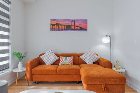 A stylish lounge with a warm-toned sofa, plush pillows, and wall art.
