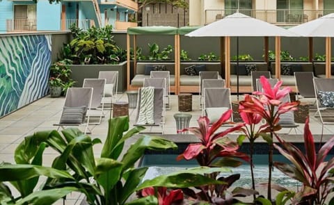 Sip cocktails as evening lights glow beside the shimmering pool.