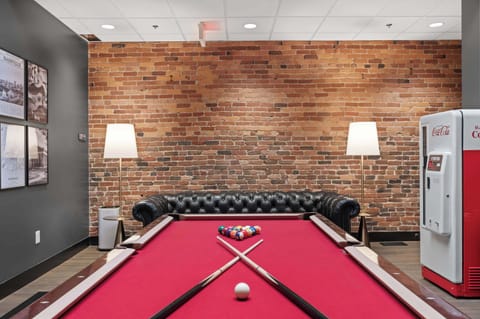 Play a round on the full-size red felt pool table, complete with cues, seating, and warm ambient lighting.