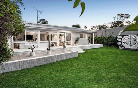 The lush lawn and spacious backyard is complete with a picnic table and outdoor shower, perfect for kids to run and play