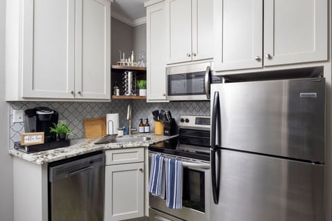 Modern kitchen with ample cabinets and a stainless steel refrigerator, fully stocked with kitchen essentials — perfect for home-cooked meals.