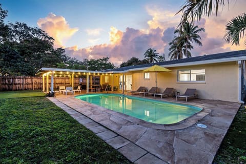 Pool and lawn at dusk, with the covered patio lit behind.