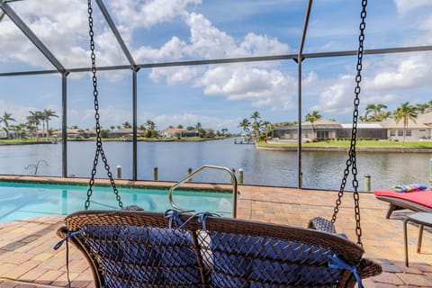 - Relax in a cozy swing overlooking a serene waterfront, perfect for morning coffee
- Enjoy the refreshing pool framed by stunning canal views under a clear blue sky
- Watch boats glide by and savor peaceful sunsets from your private screened patio