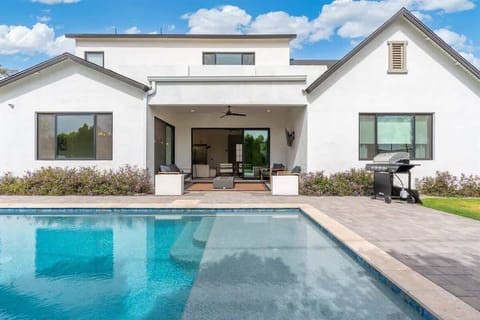 Sunlit backyard with a clean-lined pool and modern patio creates an easy rhythm for slow afternoons, quick dips, and lounging by the water. The crisp white exterior and open layout frame the outdoor space for relaxed, open-air moments.