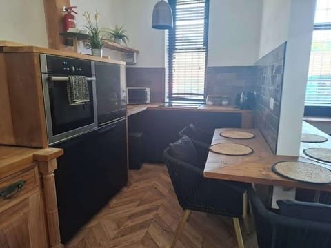 Kitchen with wraparound dining and desk
Open kitchen with wraparound counter that doubles as a dining bar and workspace, perfect for remote working or casual meals at Hosterooo (Rochdale).