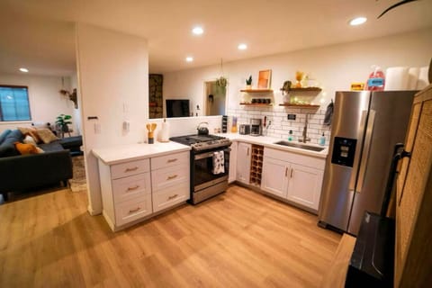 Fully equipped stylish kitchen with open shelving and stainless steel appliances.