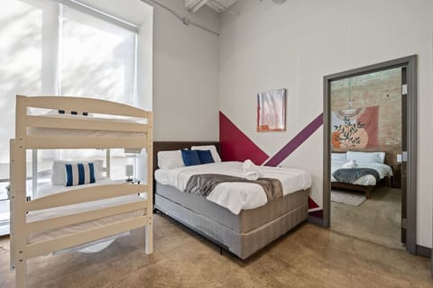 Shared bedroom in Dallas with queen bed, bunk bed & geometric wall art—stylish retreat blending comfort and design.