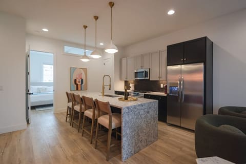 Modern kitchen with a marble island, bar seating, and stainless steel appliances.