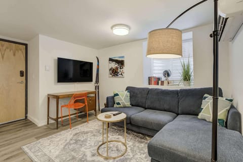 Cozy and stylish living space with a plush sectional, Smart TV, and a dedicated workspace—perfect for relaxing or working remotely.