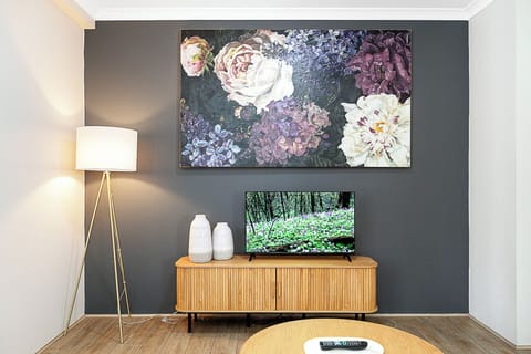Enjoy entertainment in a cozy living room, showcasing a floral art, a smart tv, and ambient lighting.