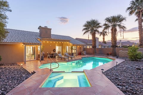 Your glowing desert retreat with pool, spa, and palm trees at twilight.