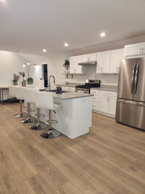 Stainless steel appliances, white leather bar stools, and large center island