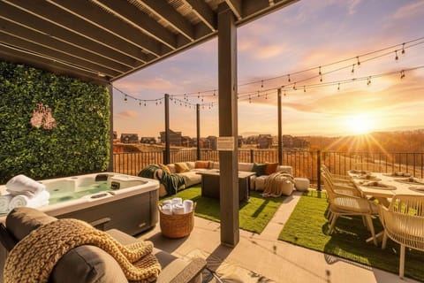 Outdoor patio with a hot tub, lounge seating, and dining area overlooking a sunset view.