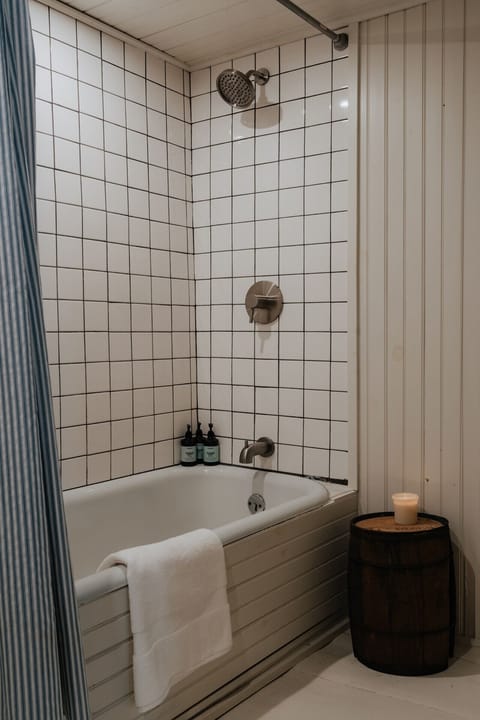Unwind in the Austen Room’s ensuite bathroom, featuring a classic bathtub and a beautifully tiled shower. Whether soaking after a long day or enjoying a refreshing rinse, this space offers a spa-like experience.