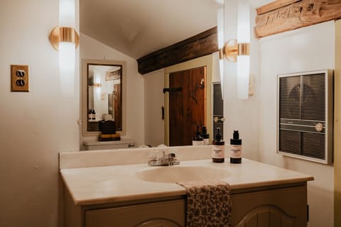 A blend of old-world charm and modern comfort—the Fitzgerald Room’s detached private bathroom features a spacious vanity, elegant lighting, and warm wood accents.