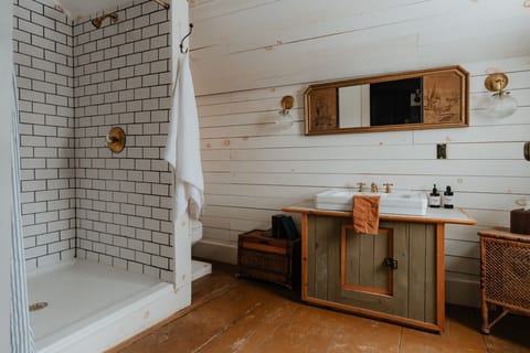 A stunning ensuite bathroom with double vanity, rustic wood finishes, and a walk-in shower. Thoughtfully designed to provide comfort and style.