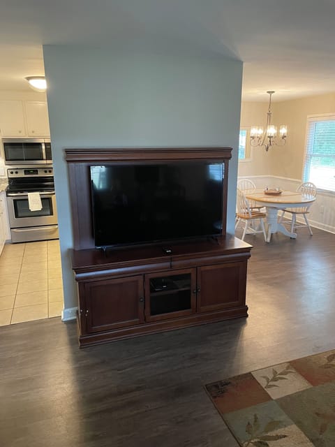 Big screen tv in the living room, with a very open floor plan to the dining area