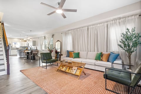 Modern living room with white sectional, bold accents, and natural light.
