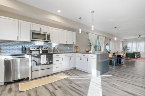 Sleek kitchen with blue tile, white cabinets, and stainless steel appliances.
