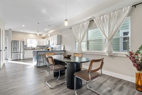 Dining area with black table, retro chairs, and open layout for meals or games.
