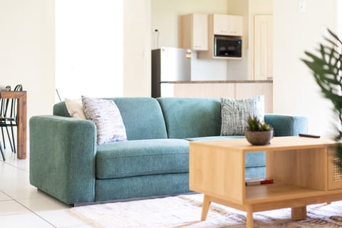 Spacious Living Room Relax on the emerald green 2.5-seater couch with a mini wooden table and Smart TV for your entertainment.