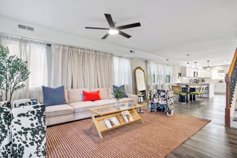Stylish open-concept living room with bold chairs, plush sofa, and mirror.
