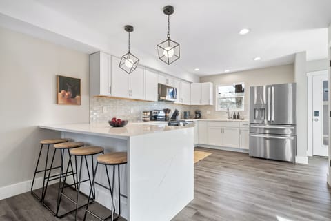 Modern kitchen with quartz island, stainless appliances, and seating for four.