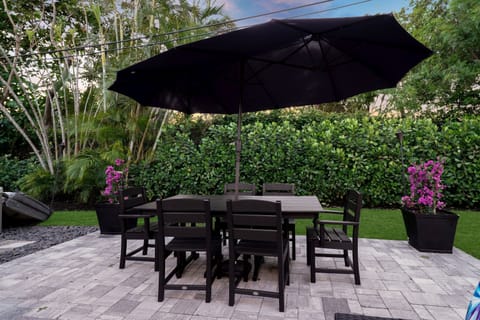 Enjoy meals in the fresh air at this inviting outdoor dining space, complete with a large table, comfortable seating, and a shady umbrella.